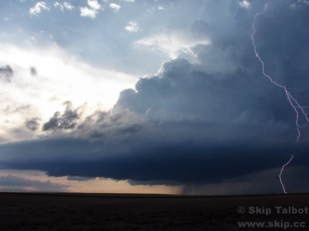 The updraft tower of a supercell thunderstorm with a bolt of cloud to ground lightning