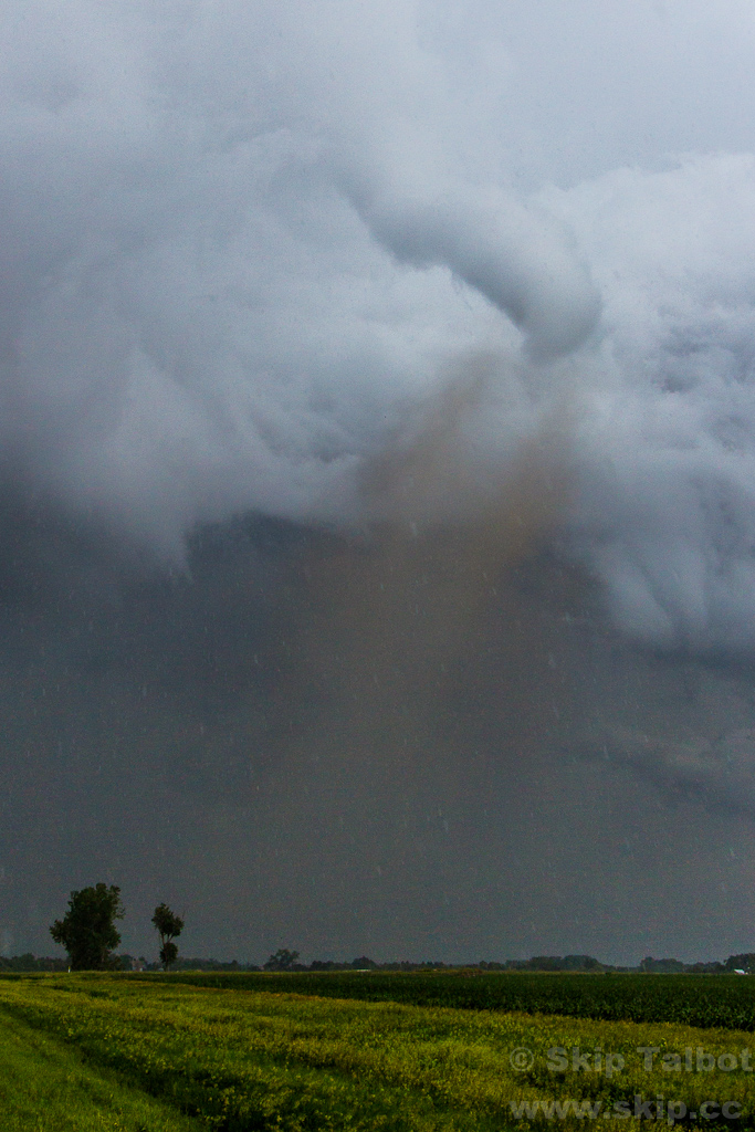 A tornado with a claw shaped funnel and dusty brown debris cloud